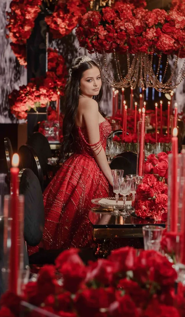 Chica con vestido rojo en celebración con rosas y velas rojas gracias a la planeación y diseño de eventos