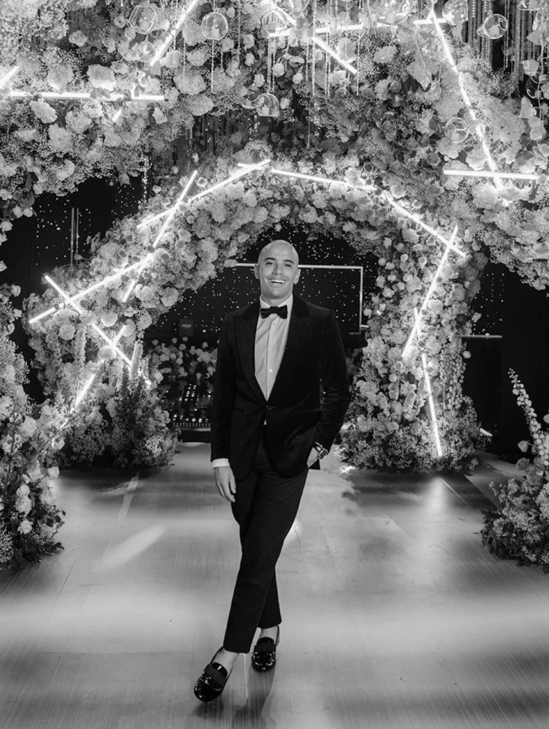 Event planner David Betancur en medio de un arco de flores, estándar de ejecución