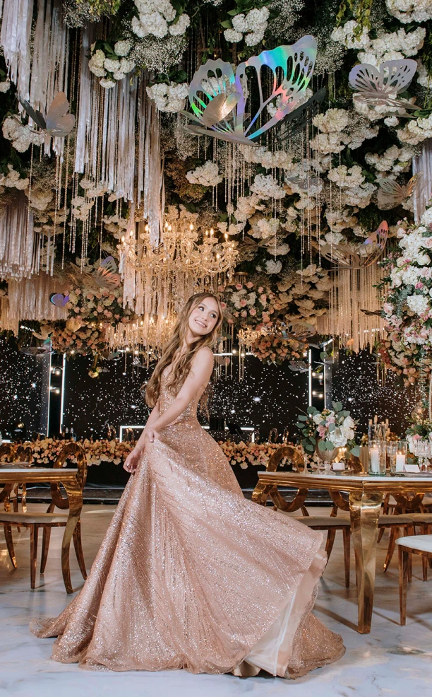 Chica feliz en salón elegante con arreglos florales y candelabros en el techo