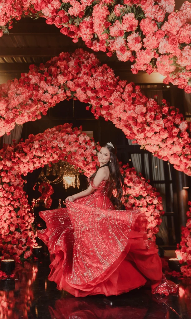 Recuerdo eterno de chica posando frente a arcos de flores rojas