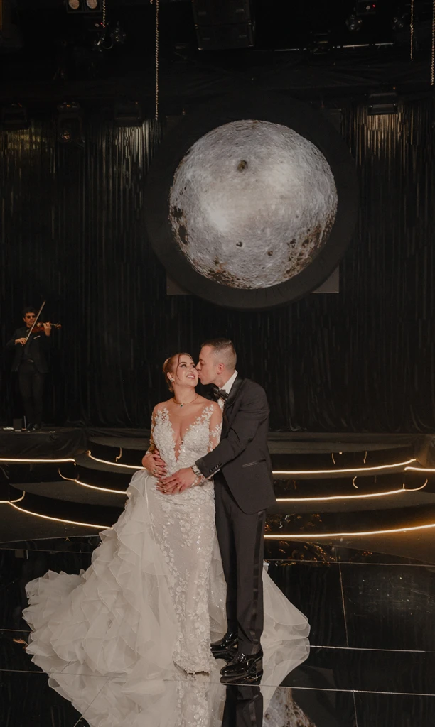 Pareja de esposos posando frente a una figura grande de la luna