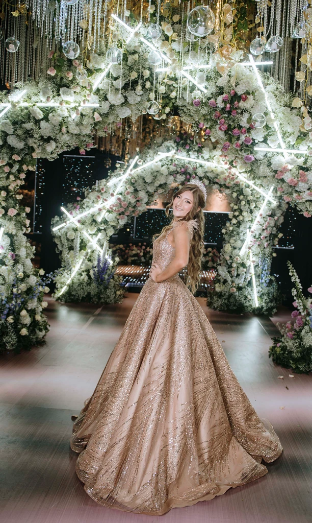 Chica posando frente a arcos de flores blancas con luces led