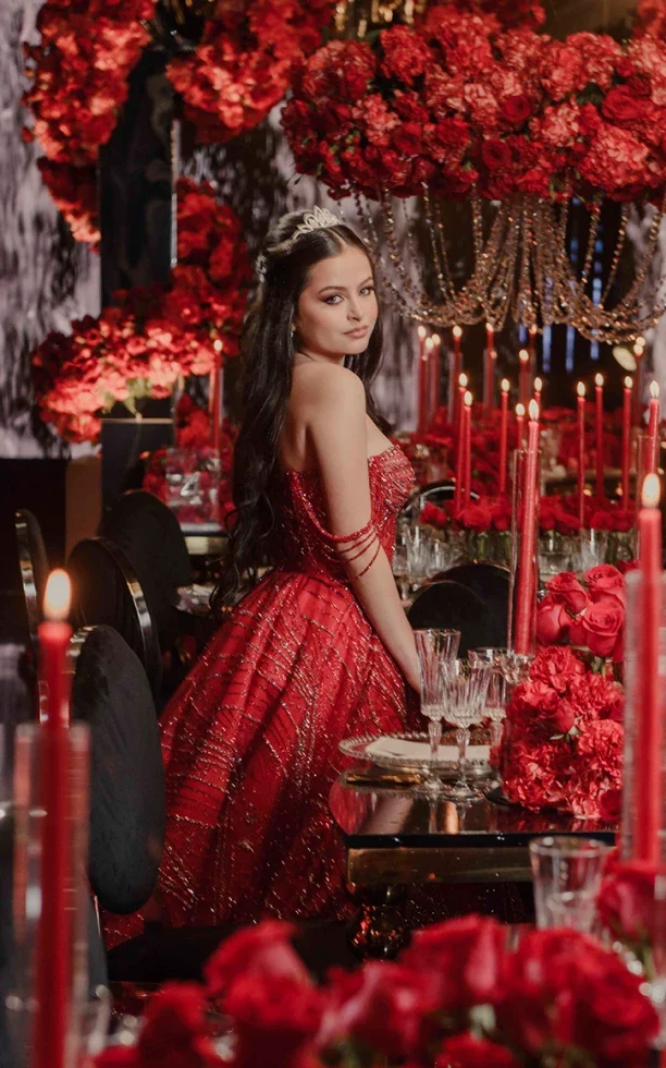 Chica con vestido rojo en celebración con rosas y velas rojas gracias a la planeación y diseño de eventos